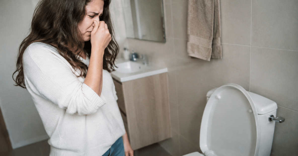 Personne se bouchant le nez devant toilettes malodorantes