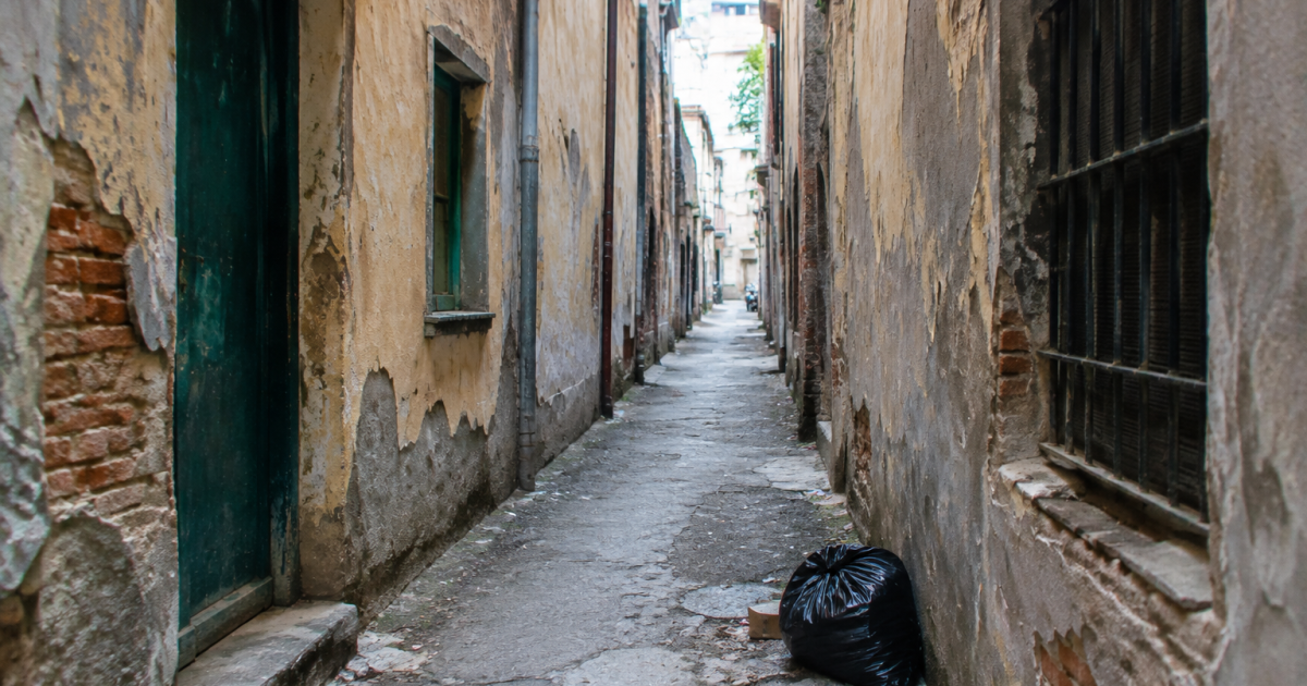 Rue etroite avec facades usees et detritus au sol