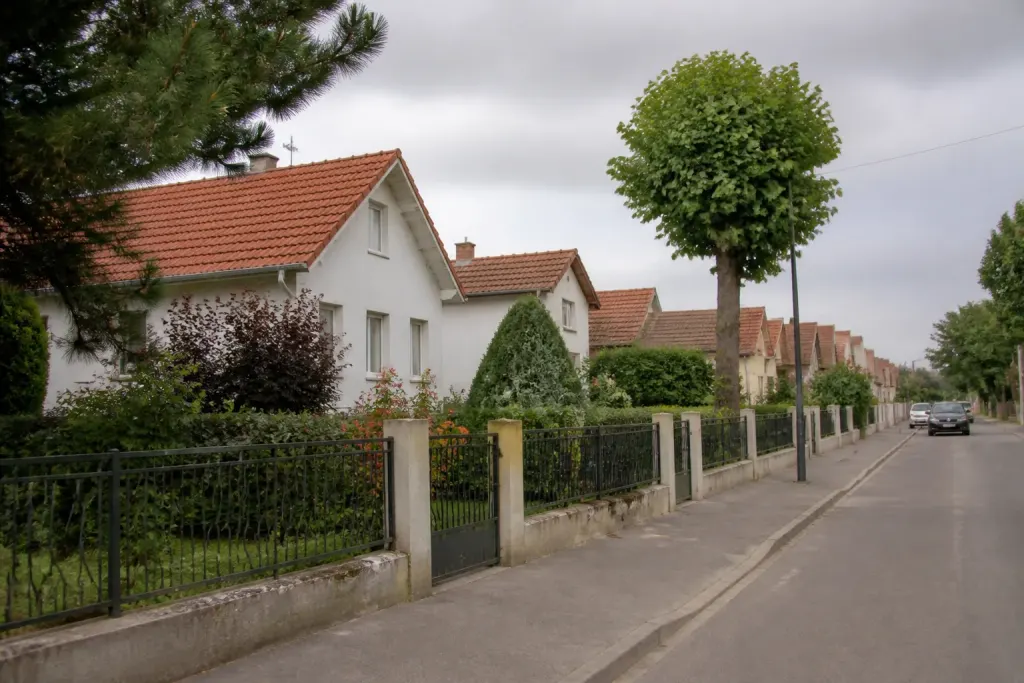 Rue résidentielle bordée de maisons pavillonnaires avec jardins