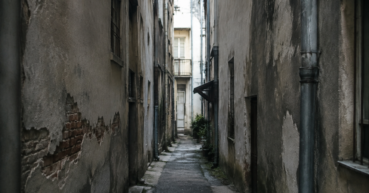 Ruelle etroite entre immeubles gris montrant signes de degradation